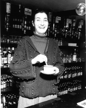 Tamara Malcom stands behind the bar stirring a cup of tea