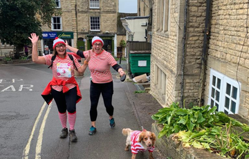 Two people running dressed as wise wally with a dog