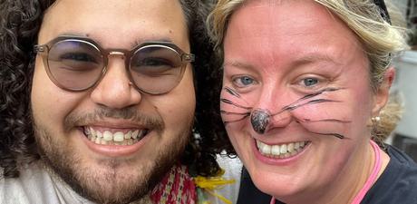 Two people smile for a slefie, one dressed as a mouse