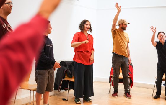 People standing in a circle with arms raised