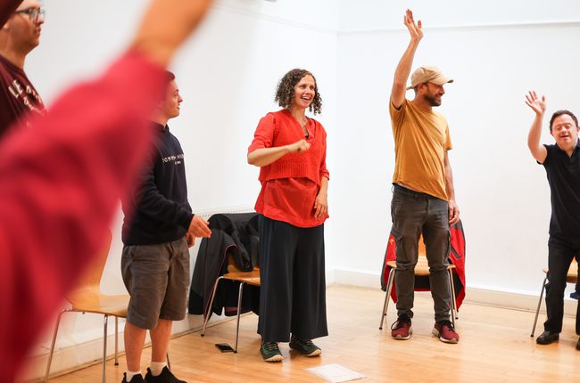 People standing in a circle with arms raised