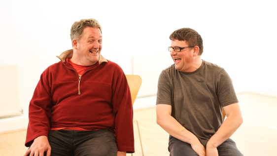two men sitting next to each other laughing