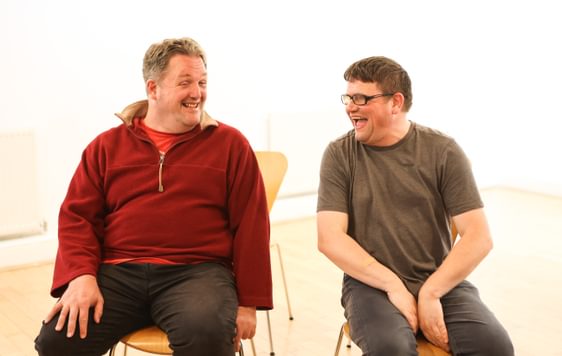 two men sitting next to each other laughing