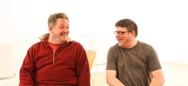 two men sitting next to each other laughing