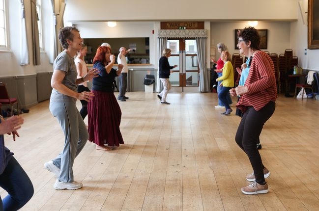 Two lines of people are facing each other as though they are paired up for a dance.