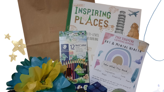 A photo of a mental health pack with mindful colouring book, colouring pencils, stickers, a tissue paper flower, fidget cubes and booklet.