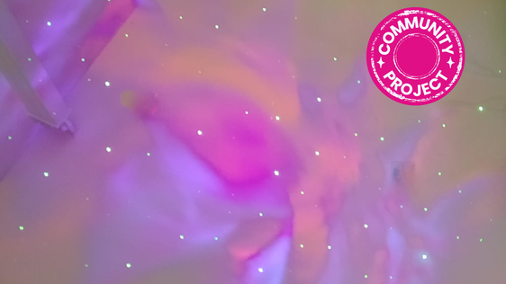 Space lights on ceiling in pink, purple and orange with Community Project badge