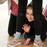 Girl peeking through legs at a theatre course