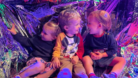 three children playing in a foil blanket