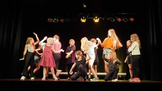 A group of children participating in fast paced movement onstage.