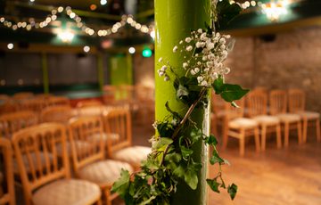 Wedding flowers pinned to pillars in Auditorium with chairs in the background