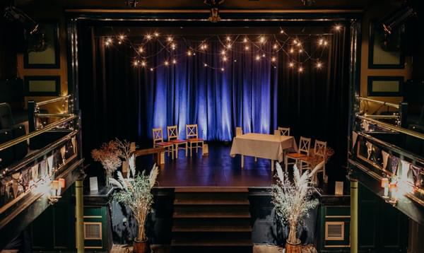 Theatre set up for a wedding ceremony with lights, pampas grass and flowers