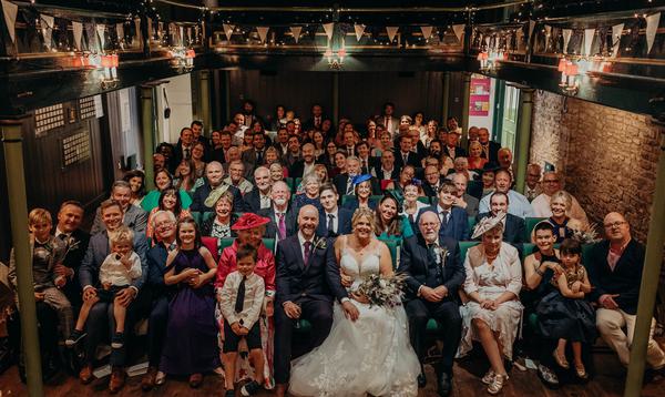 Bride and groom at the front and wedding guests all sat in theatre stall seats